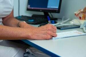 Consult ORL – medic completează fișa pacientului în cabinet, după o consultație clasică sau online.