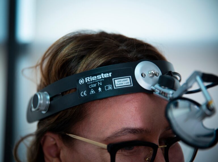 Medic ORL purtând lampă frontală profesională Riester, utilizată pentru examinări detaliate ale urechii, nasului și gâtului.