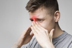 Bărbat care suferă de congestie nazală severă cauzată de rinită cronică hipertrofică, evidențiată prin zona inflamată a sinusurilor.