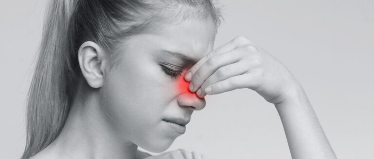 Femeie cu durere intensă în zona nasului, simptom tipic al cefaleei rinogene provocate de afecțiuni ORL.