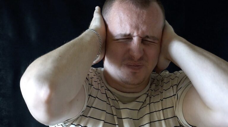 Bărbat care își acoperă urechile din cauza tinitusului – informații esențiale despre acufene și cum pot fi gestionate