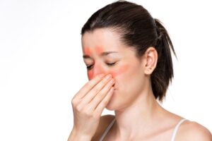 Femeie care își masează nasul și zona sinusurilor, evidențiind congestia nazală, cu un accent pe tratamente și prevenirea complicațiilor.